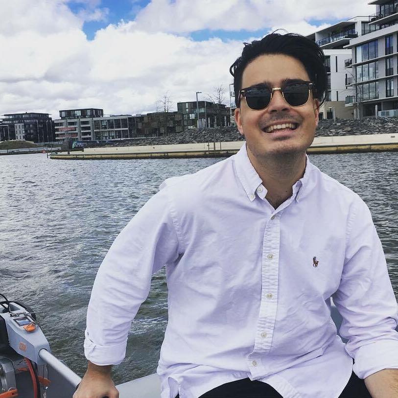 Former ACT Young Labor president Nick Douros sits on the edge of a boat in a canal.