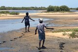Children walk on the beach with spears