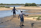 Children walk on the beach with spears