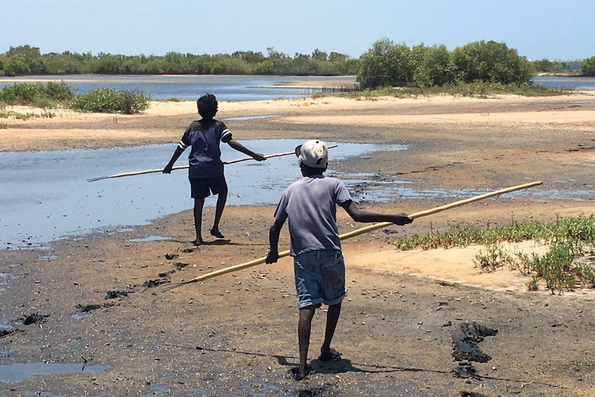 Children hunt with spears on the beach on Groote Eylandt.