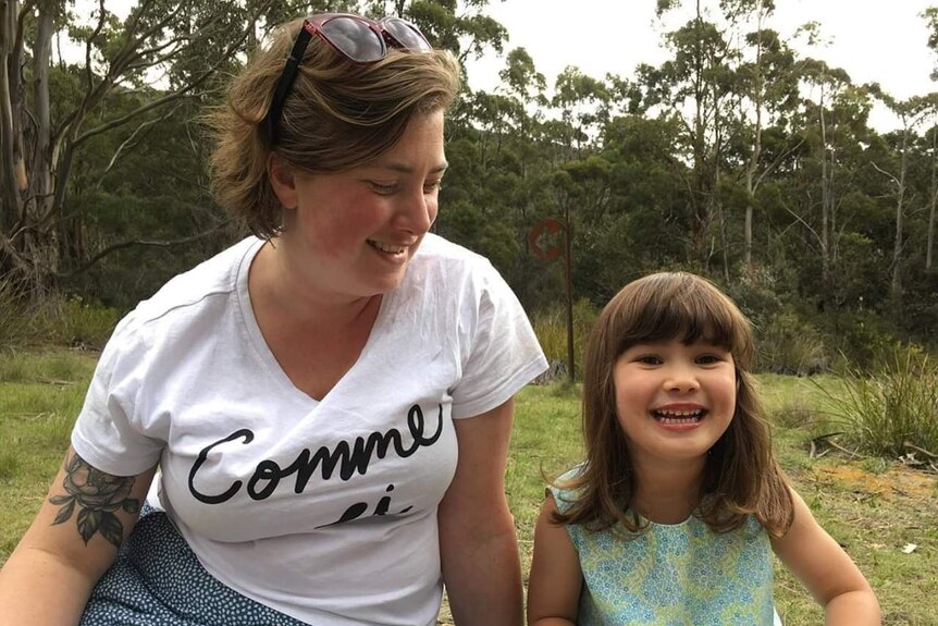 Elizabeth Clark and her daughter Sophie sit in a park in Hobart. 