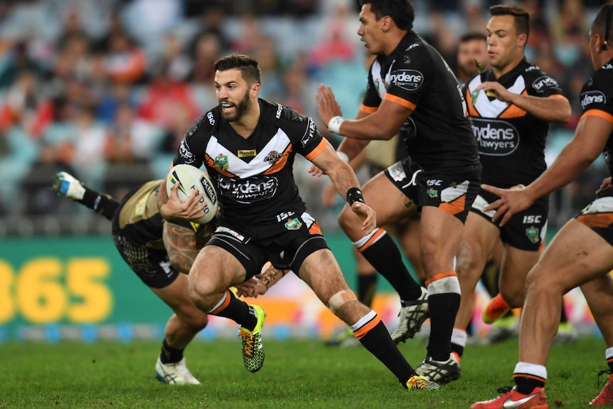 Wests Tigers' James Tedesco (L) runs with the ball against Penrith at the Olympic stadium in 2016.