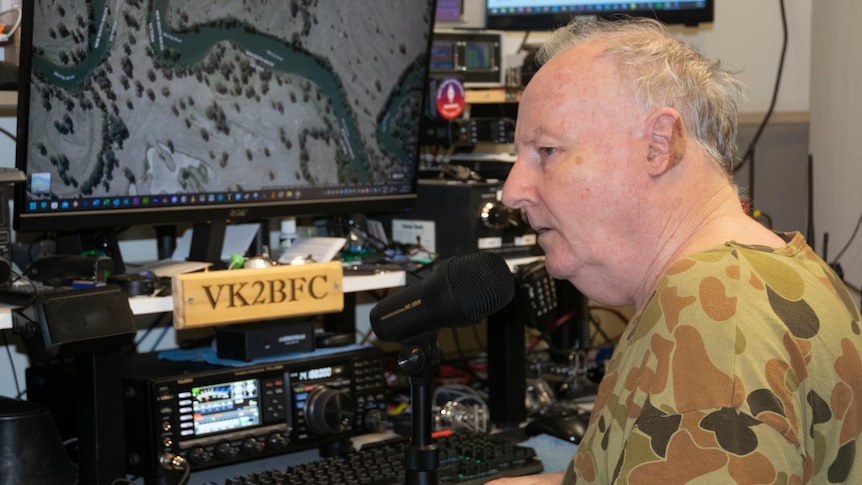 A man sits working with radio gear