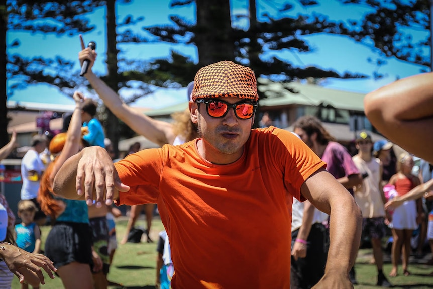 Man in orange shirt, orange cap and orange glasses, dancing