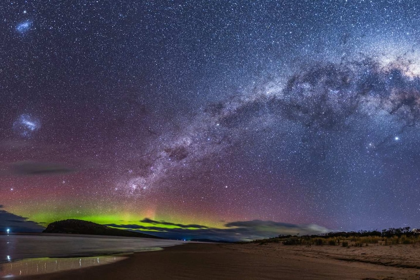 A multi-coloured milky way arching across the sky and aurora australis.