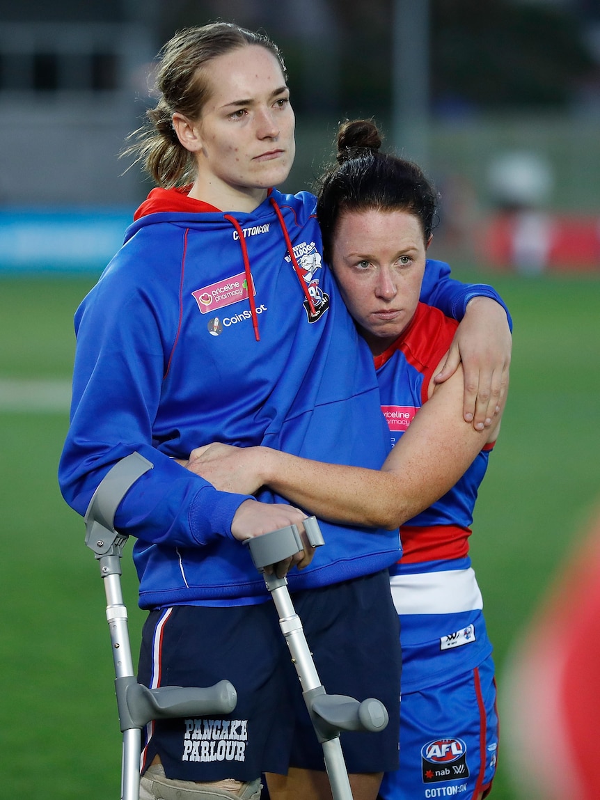 Isabel Huntington is consoled and hugged by teammate Brooke Lochland while on crutches