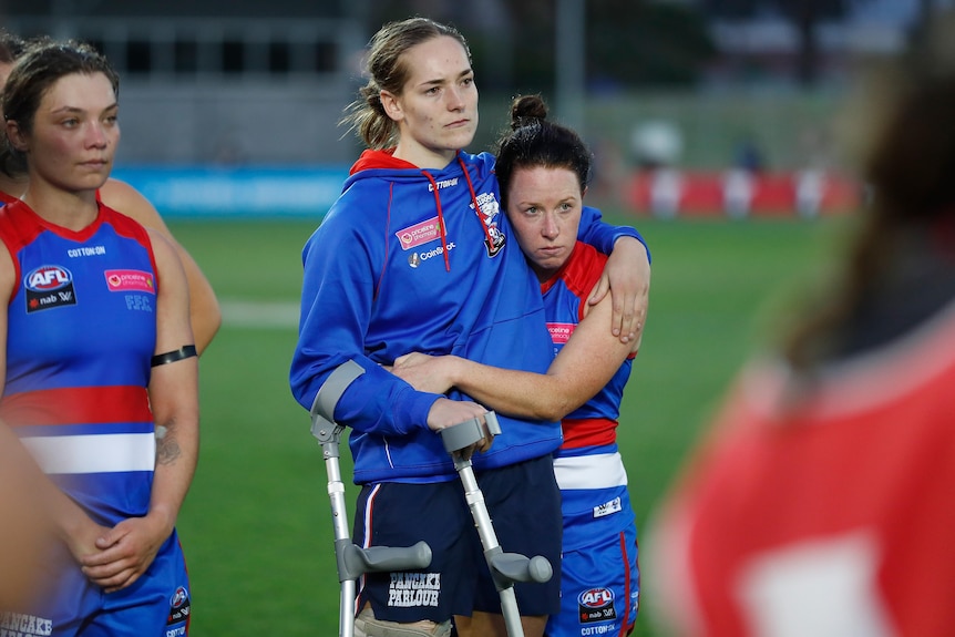 Isabel Huntington is consoled and hugged by teammate Brooke Lochland while on crutches