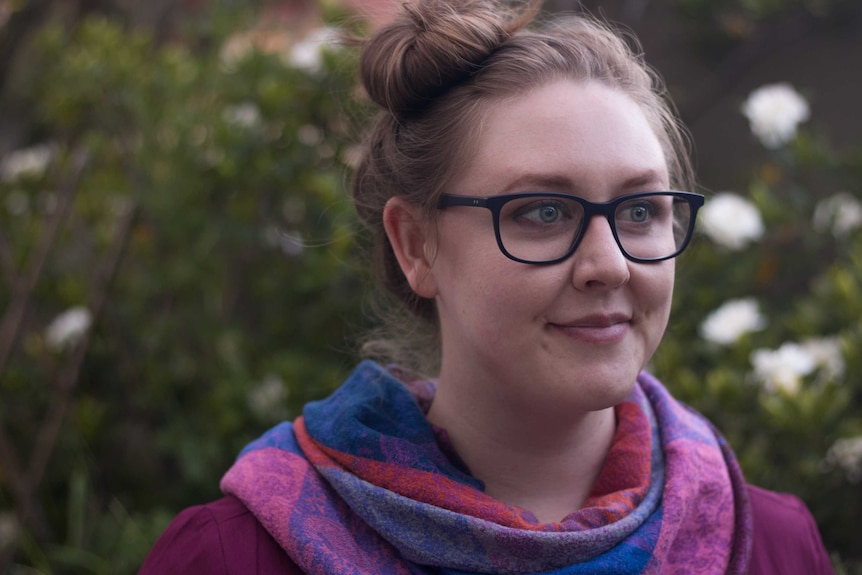 Young woman in glasses stands in garden