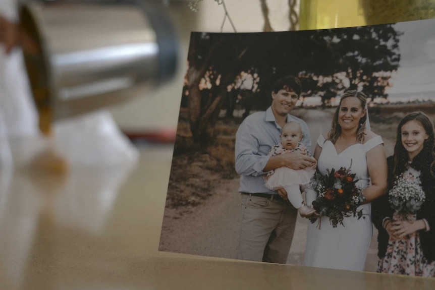 A wedding photo with a man and a woman and their two daughters sits on top of a kitchen counter