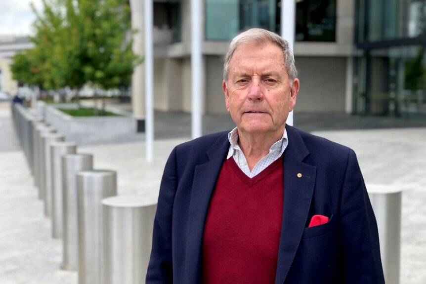 A man stands with a serious look on his face.