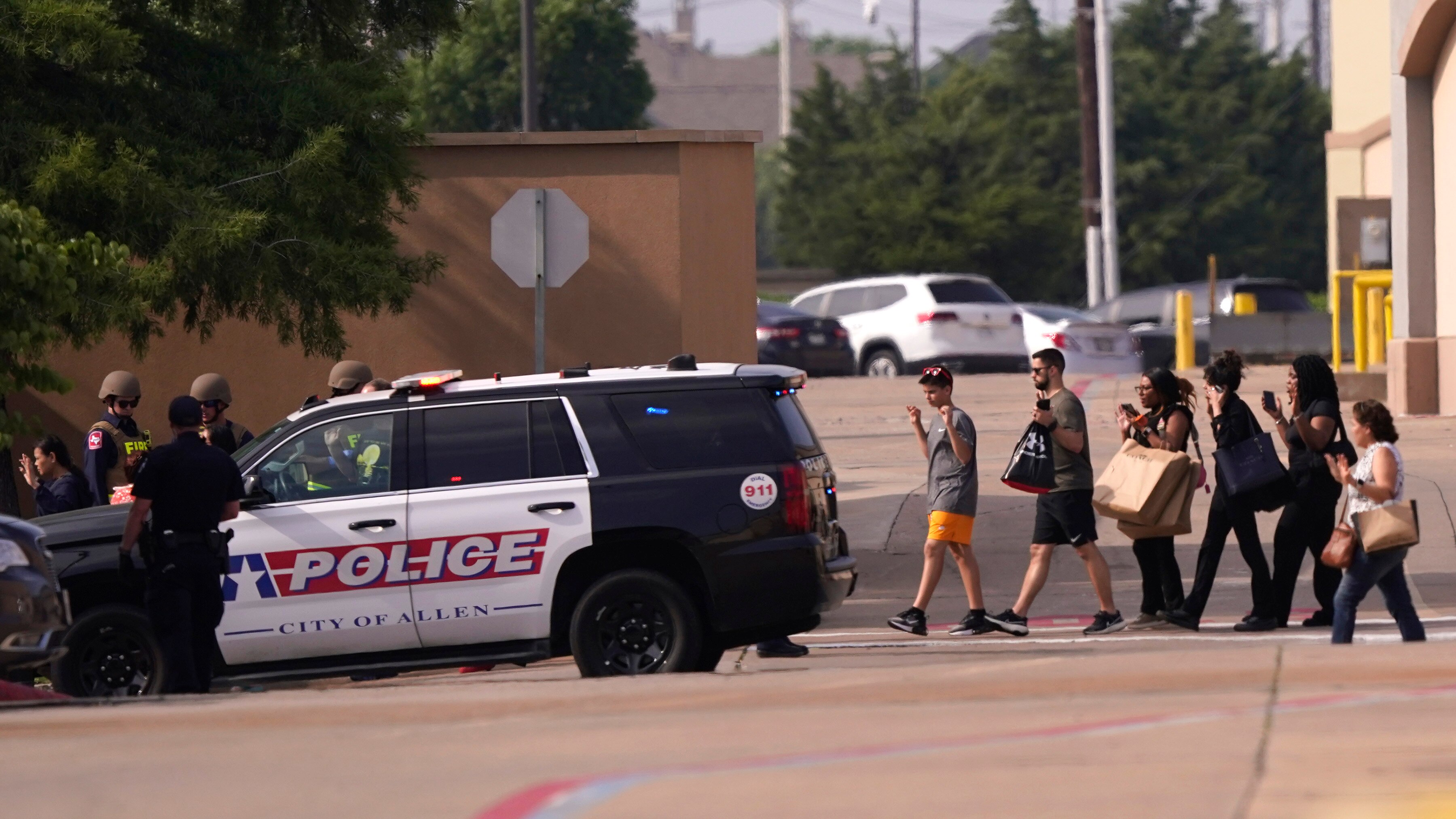 People are pictured walking towards a police car with their hands up.
