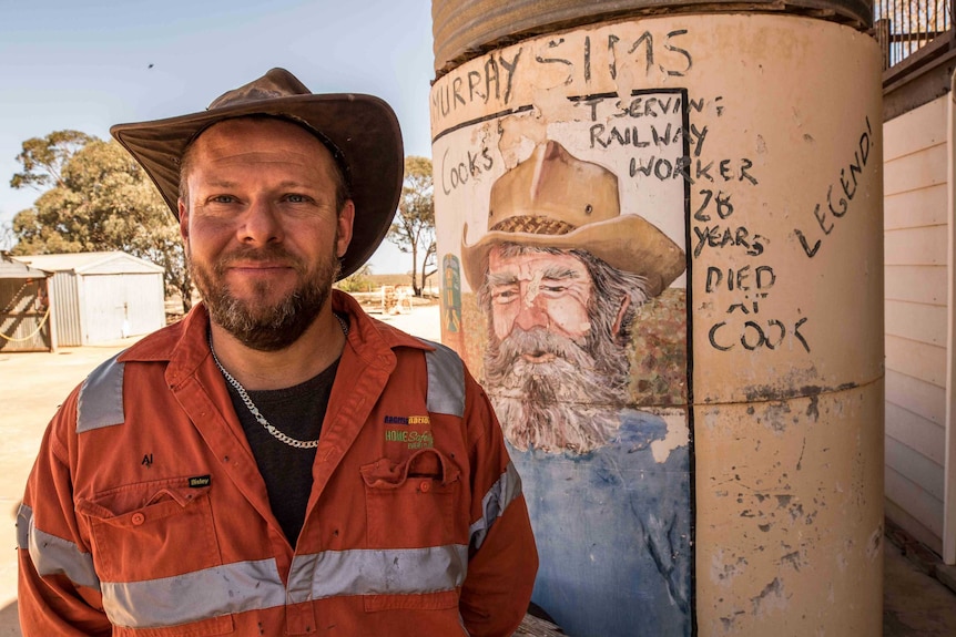 A man standing in front of an old water tank in outback Australia