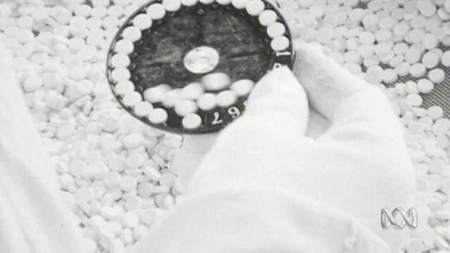 Old photo shows hand holding part of machine dispensing contraceptive pill
