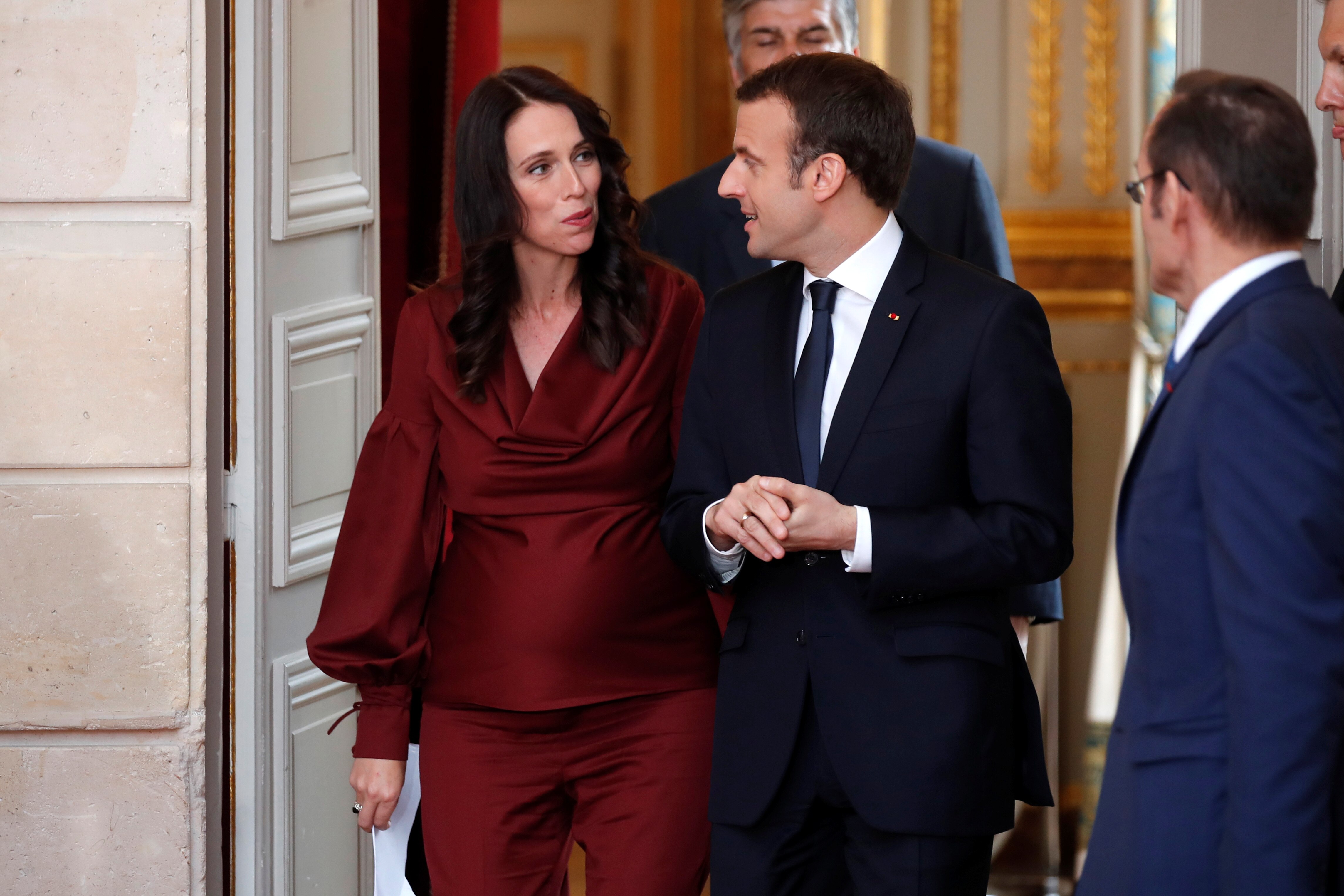 A woman, former New Zealand prime minister Jacinda Ardern, and a man, French President Emmanuel Macron, walk together.