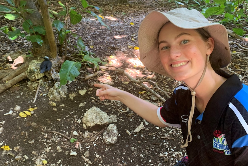 A young women point at a bird in an island setting.