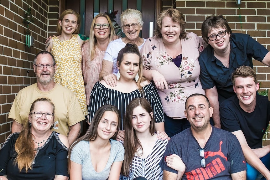 An extended family of 12 pose on the front porch for a group picture