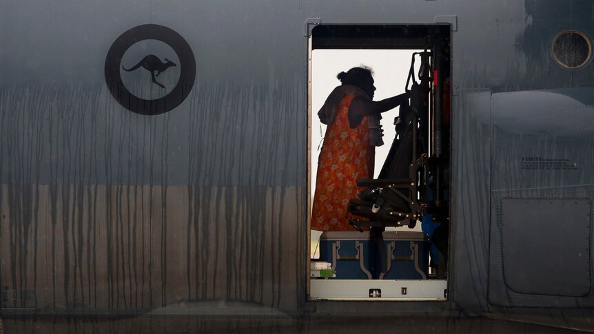 A woman boarding a Hercules after Cyclone Trevor.