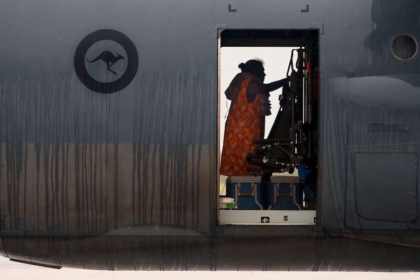 A woman boarding a Hercules after Cyclone Trevor.