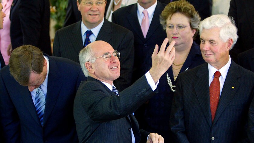 John Howard gestures as other MPs look on.