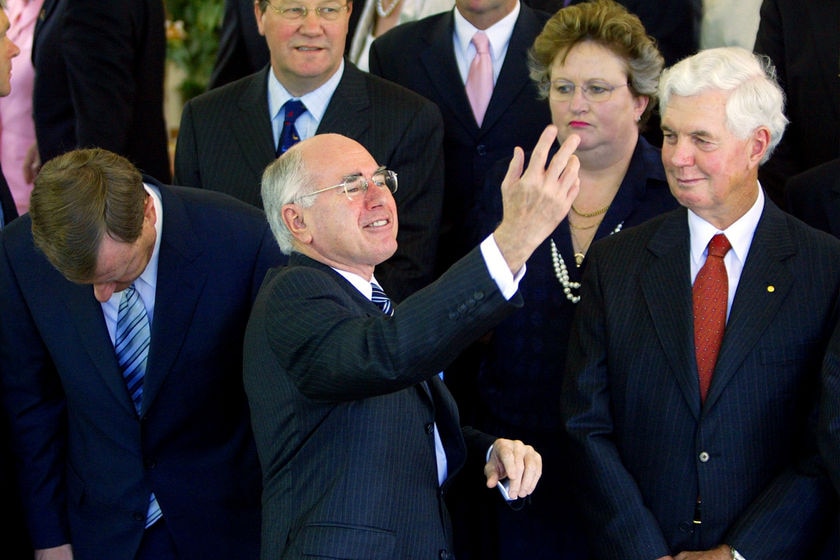 John Howard gestures as other MPs look on.
