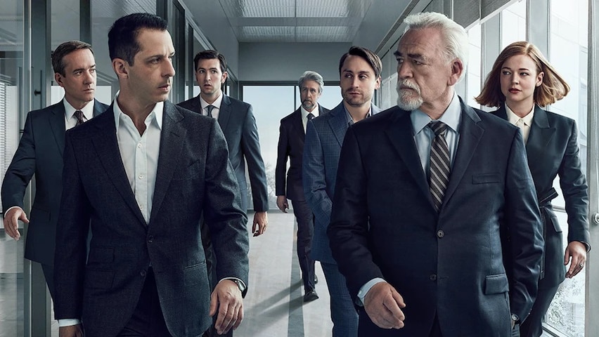A scene out of television series, Succession, 7 people are walking down a corridor wearing suit and ties.