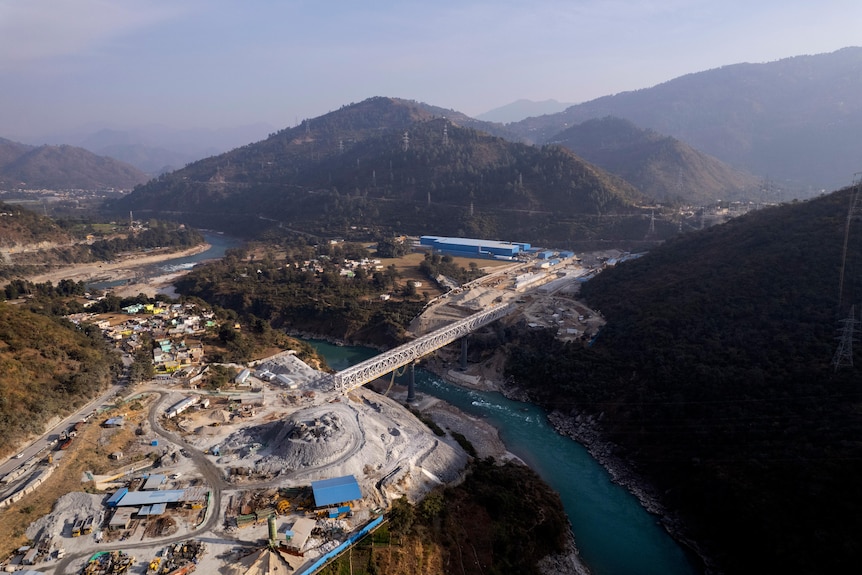 A view from above showing construction work near a body of water and mountains.