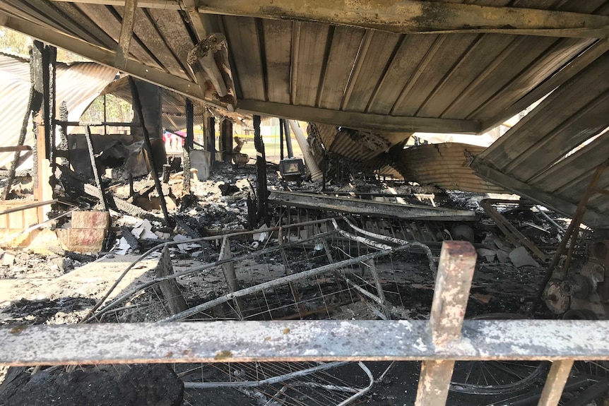 Burnt debris is all that remains within the frame of a burnt-out house.