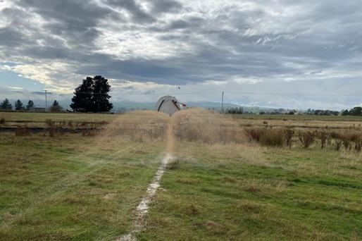 A brown substance being sprayed onto a paddock.