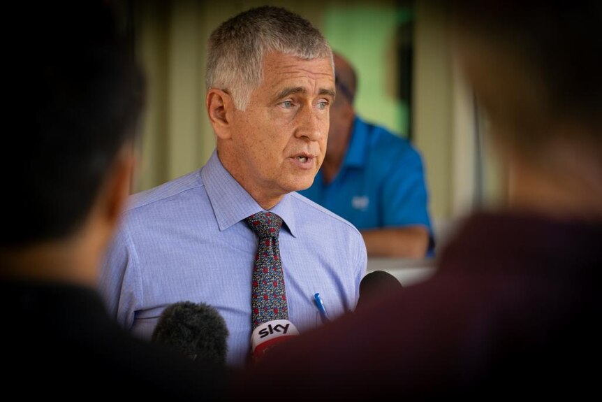 Dr Charles Pain, wears a collared shirt and tie, at a press conference in Darwin.