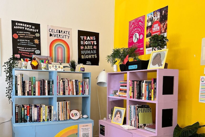 A corner of a room with brightly coloured furniture, books, and posters celebrating diversity