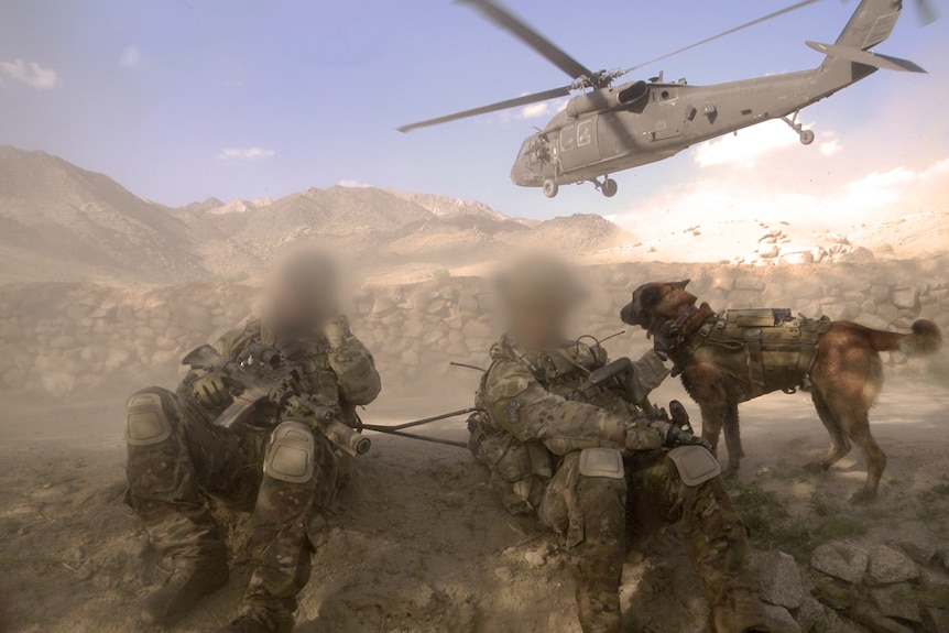 Two SAS soldiers sit with helicopter behind them