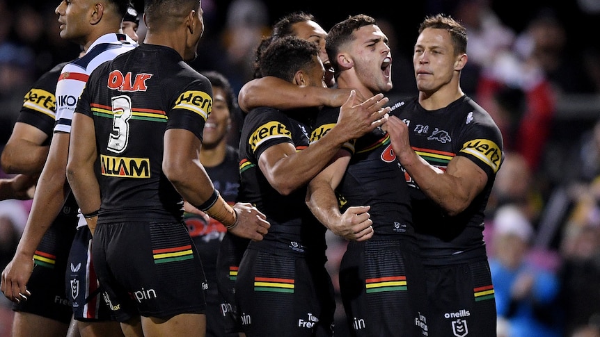 Nathan Cleary clenches his fist and screams in celebration. A number of Pantehrs teammates gather around him