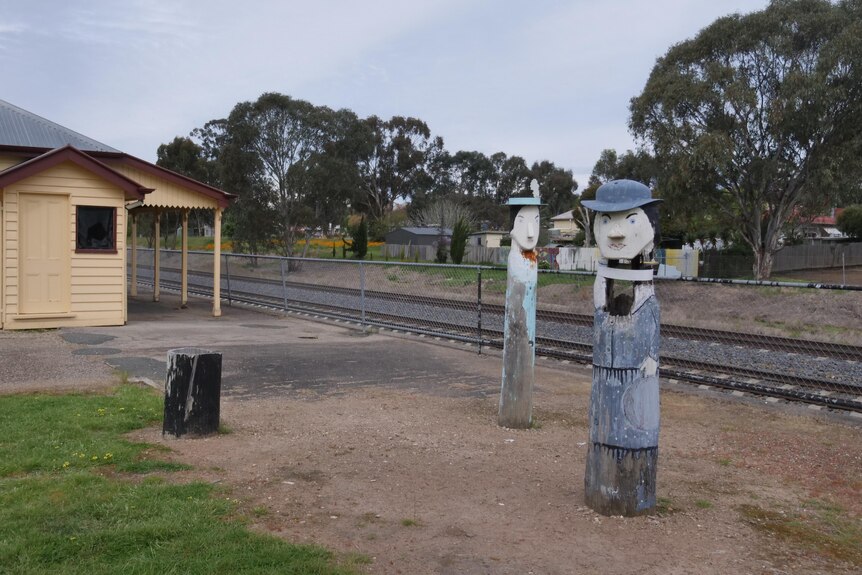 Restored railway station with cartoonish wooden sculptures of two commuters 
