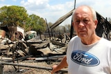 A man in front a destroyed house.