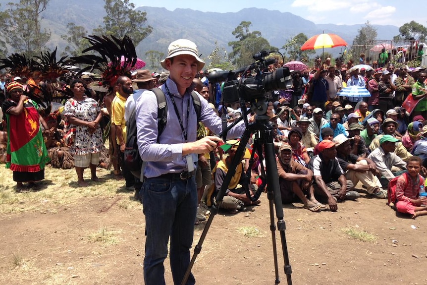 Eric Tlozek stands with his camera among a group of villagers at a political rally in Chimbu Province