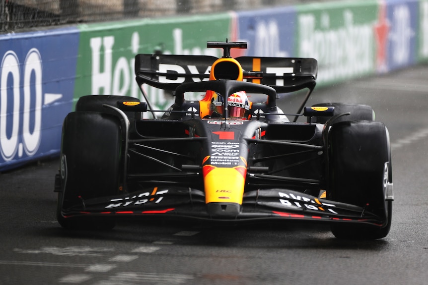 An F1 car driving on a street circuit, close to a barrier, pointing directly at the camera.