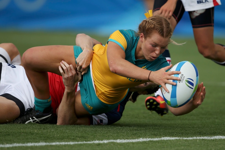 Woman with rugby ball makes a lunge for the try-line