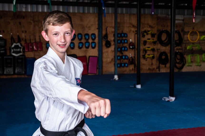 A 13-year-old boy in a karate suit, with a black belt, goes through his moves