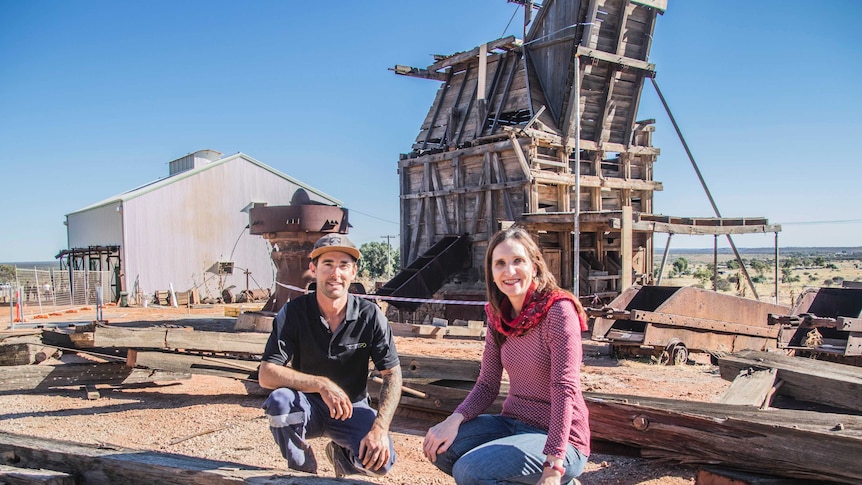 Two people beside old mining equipment