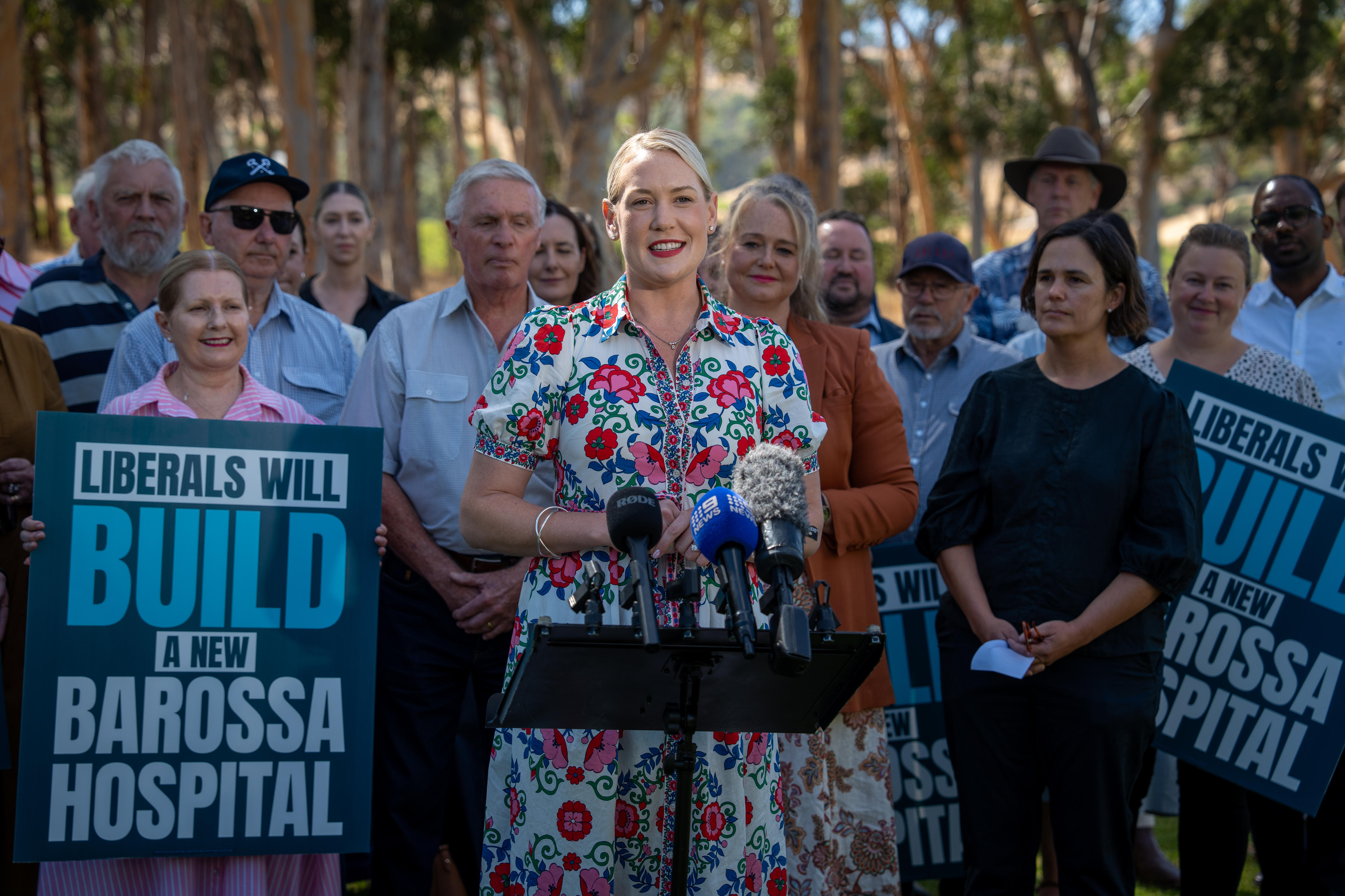 Ashton Hurn habla por micrófonos rodeado de seguidores, algunos con carteles de apoyo a un hospital de Barossa.