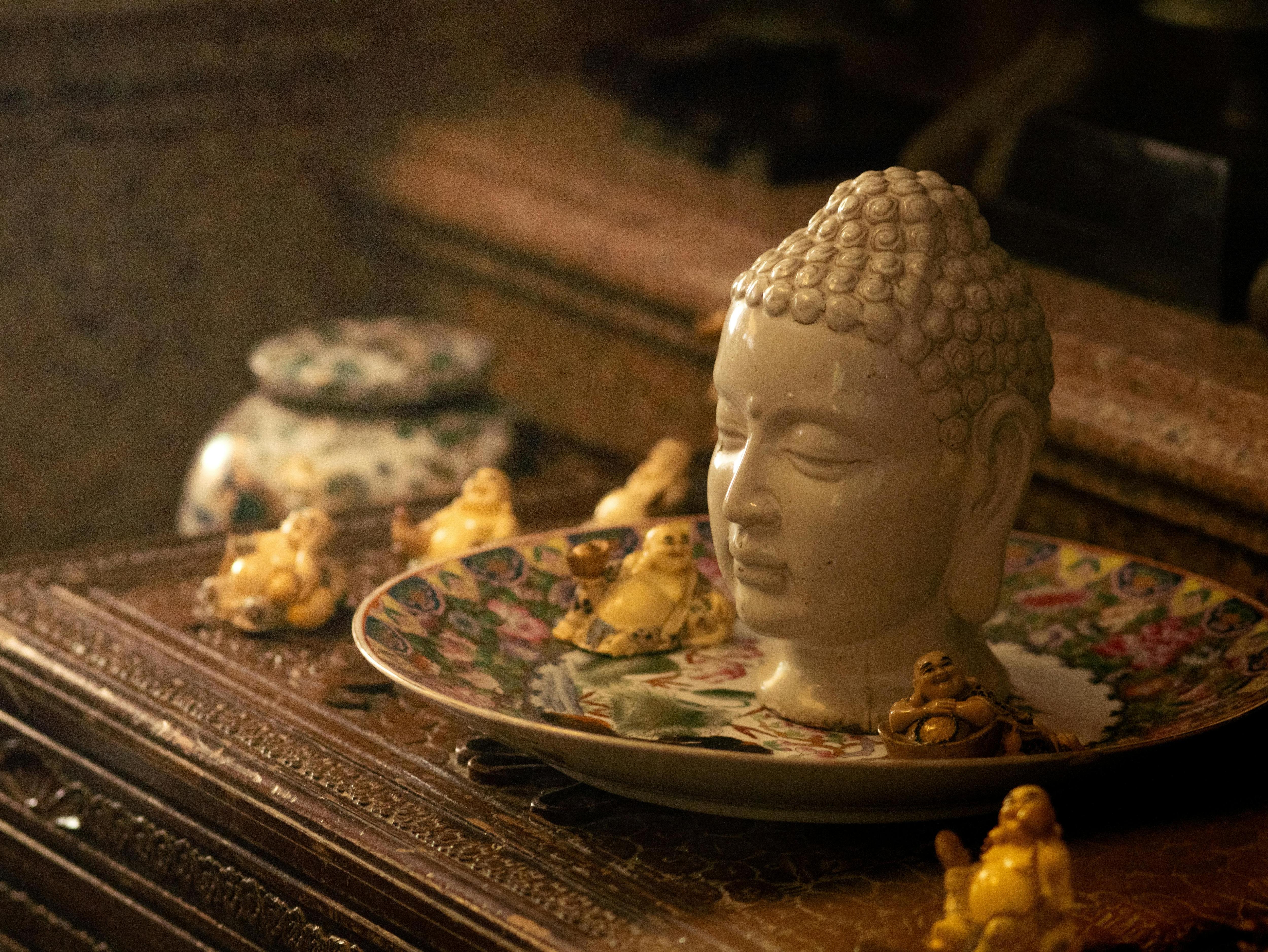 Ceramic Buddha head and figurines on an ornate plate