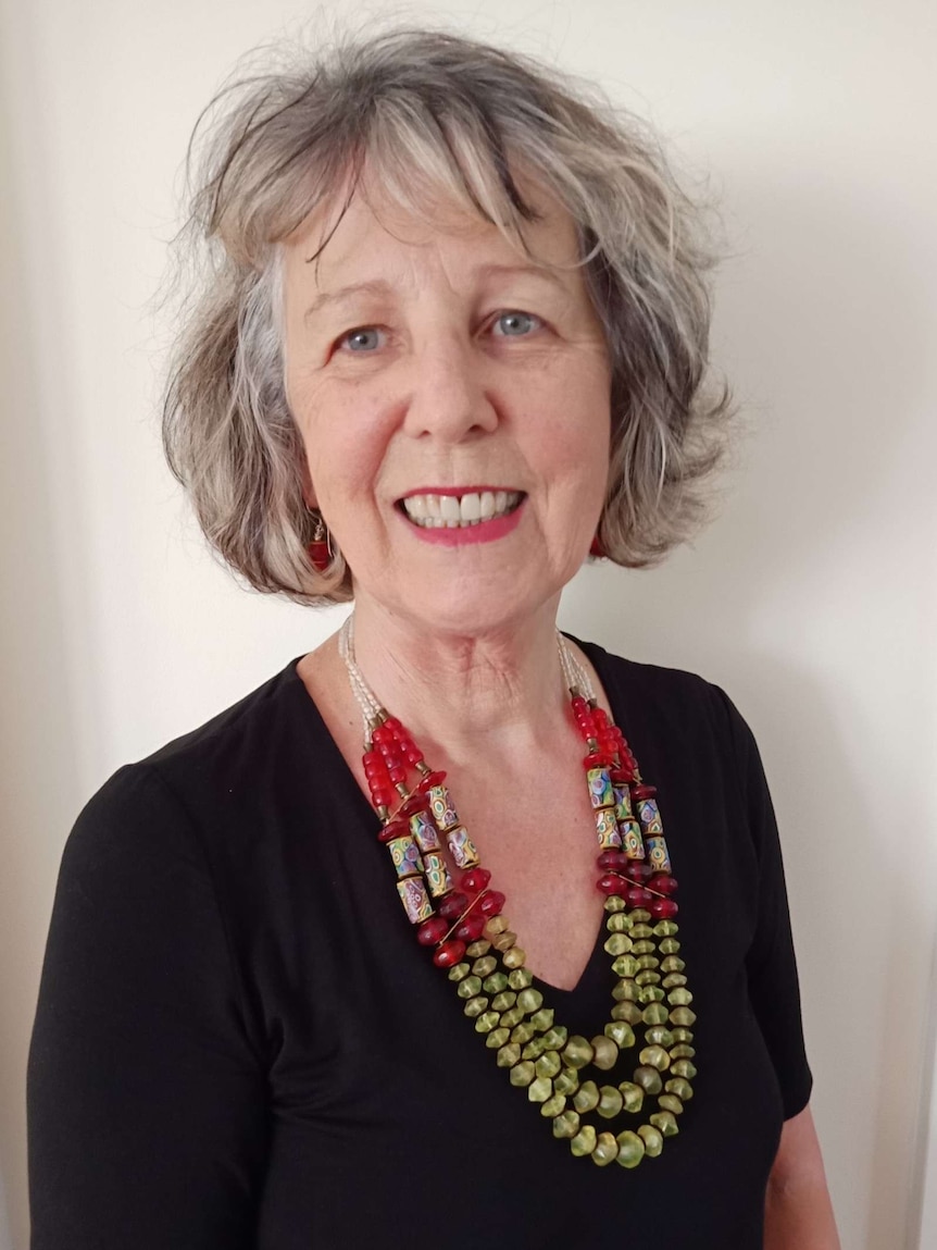 Portrait of a mature-aged woman wearing a colourful necklace and black top.