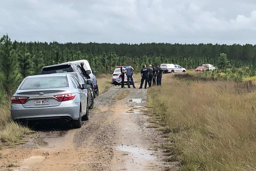 Police establish crime scene after the bodies of a man and a child are found in a red car at Coochin Creek camp grounds.