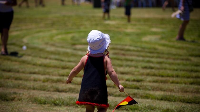 Child runs with Aboriginal flag at Saltwater-Freshwater festival, Coffs Harbour Australia Day 2010