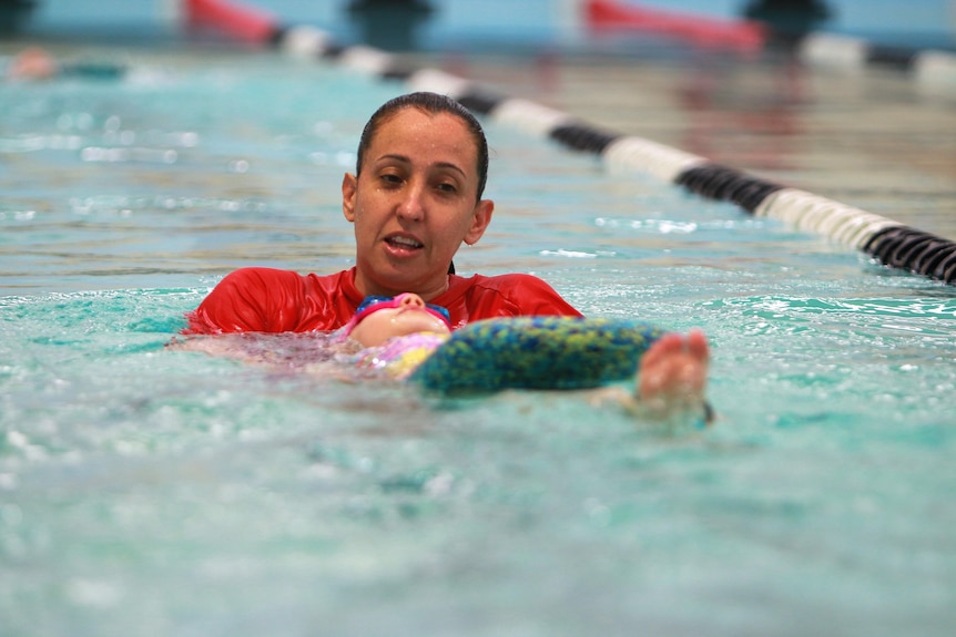 A woman giving a swimming lesson to a small child