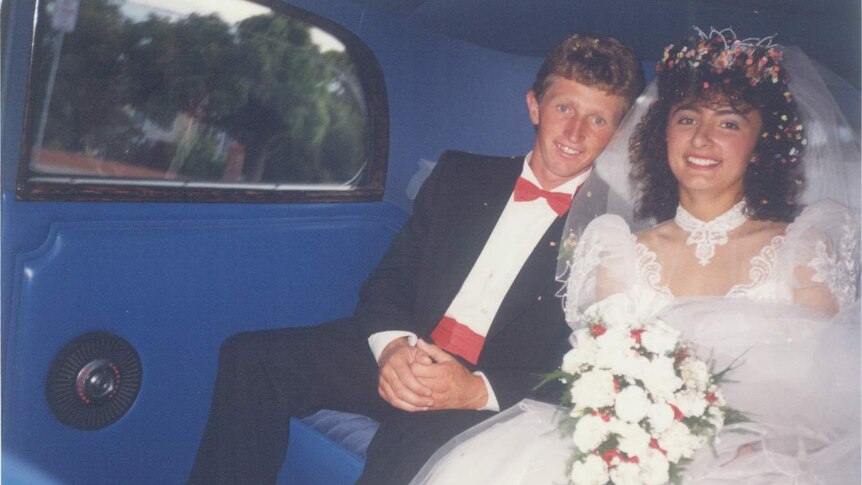 A 1980s bride and groom in the back of a car.