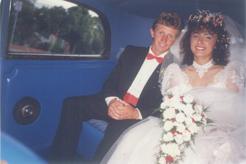 A 1980s bride and groom in the back of a car.