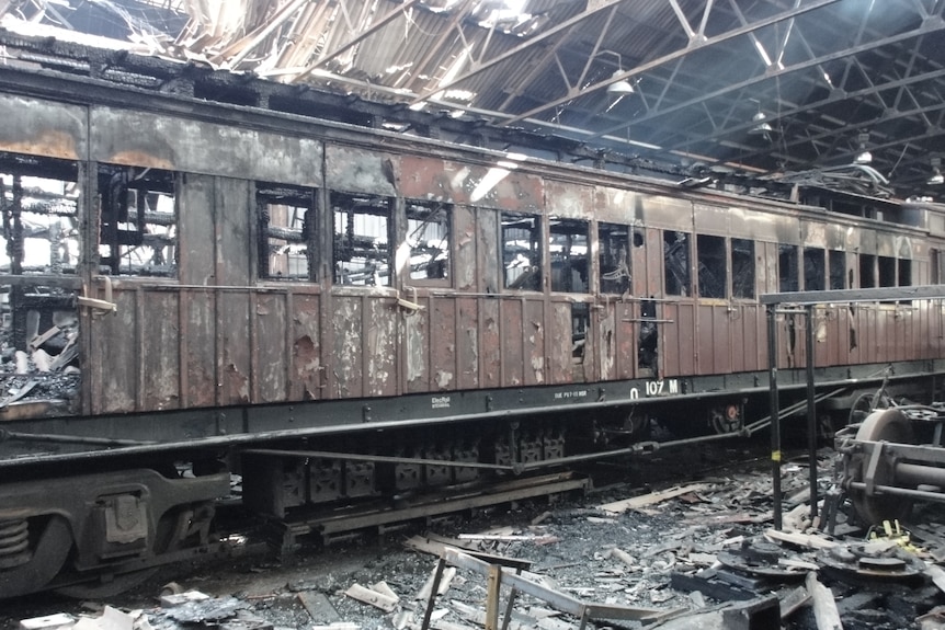 a burnt historic train carriage inside a burnt historic shed