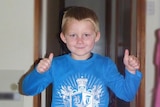 Bradyn Dillon gives the thumbs up while wearing a blue shirt with a white pattern on it