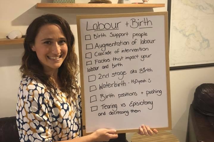 woman stands holding a sign with words about babies on it.